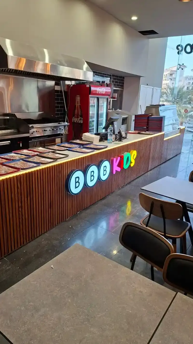 Individual illuminated letters mounted on the fluted timber front of a service counter