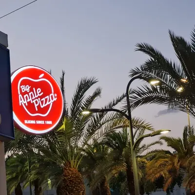 Rótulo bandera circular iluminado de doble cara, proyectado sobre una ménsula en la entrada