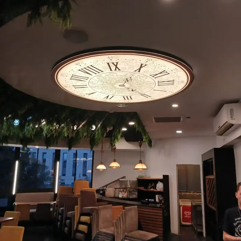 Decorative ceiling clock with Roman numerals in café interior — SignWorks