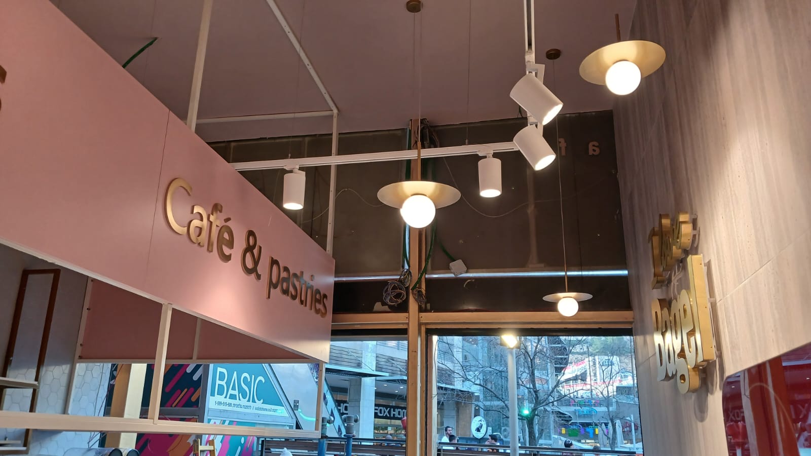 Rótulo interior de café y pastelería con letras doradas en pared rosa