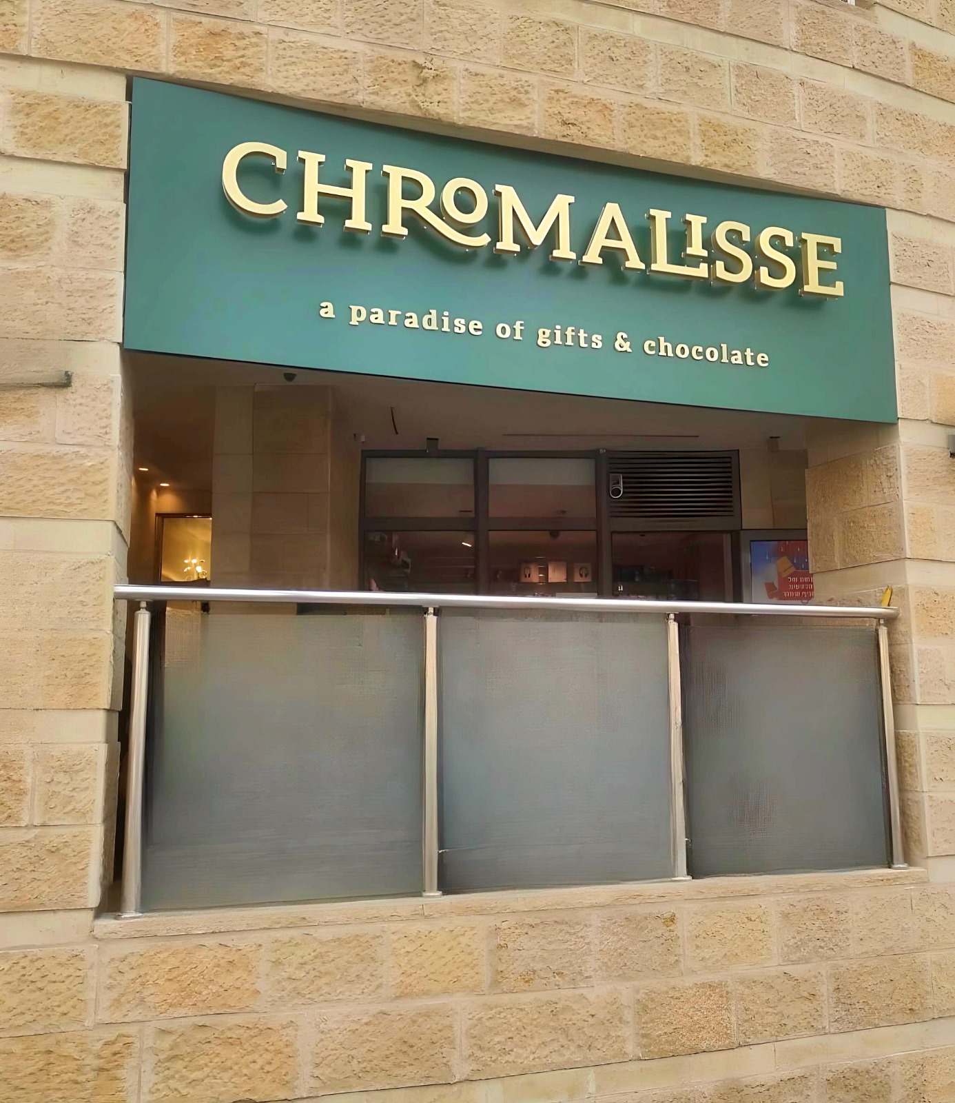 Rótulo Chromalisse — fachada verde oliva con letras iluminadas halo en dorado