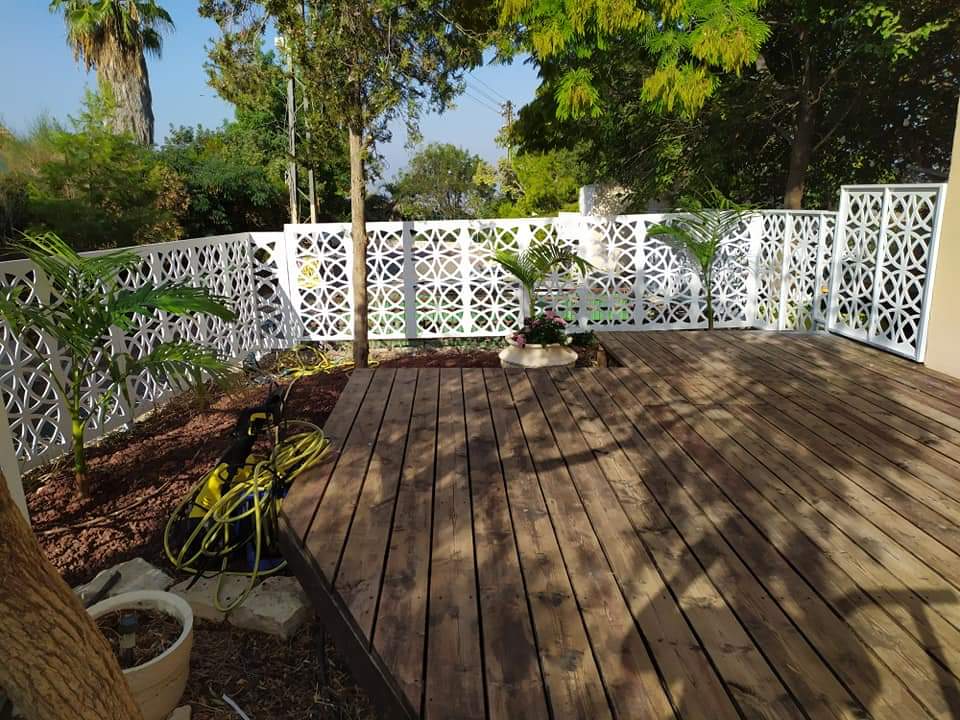 Paneles de madera cortados con CNC en estilo mashrabiya instalados como cerca de jardín en una terraza de madera en Costa Rica