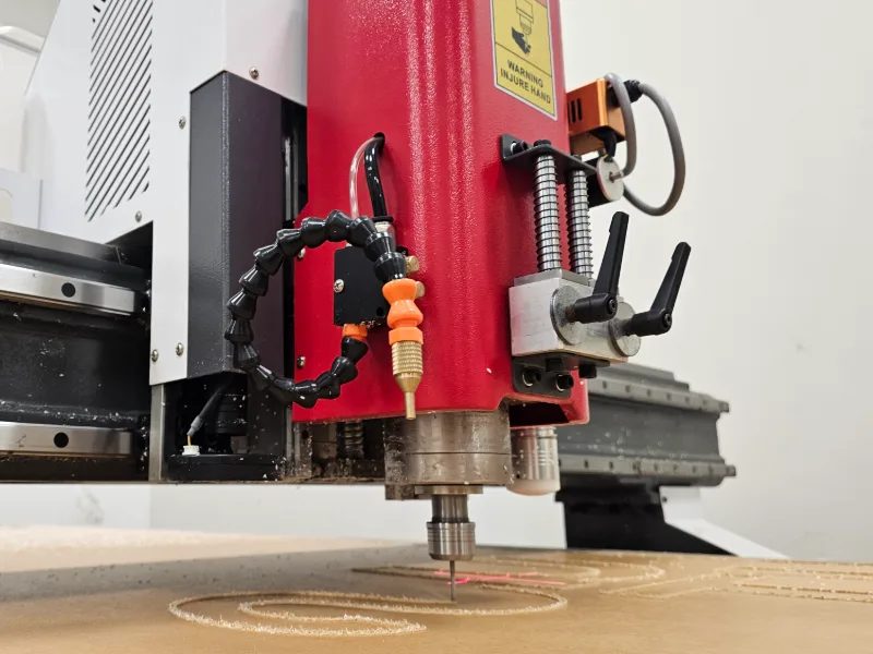 Low view of the SignWorks CNC router cutting letters, its laser guide on the acrylic, Costa Rica