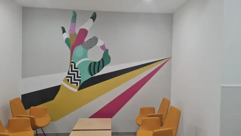 Colorful abstract hand wall mural in interior space with chairs — SignWorks