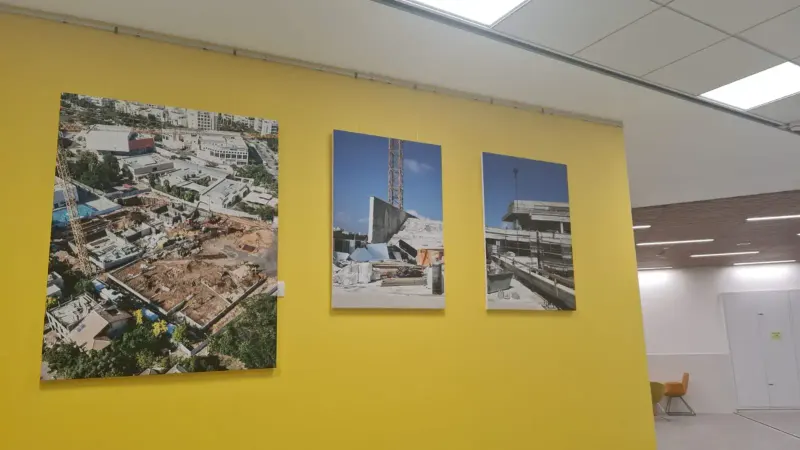 Construction site photographs displayed on yellow wall — SignWorks