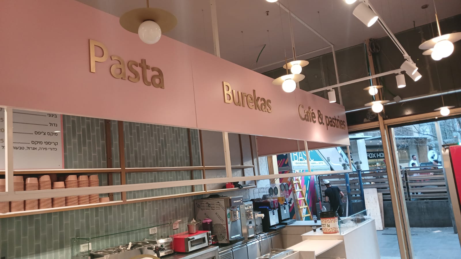Fachada de cafetería con letras doradas dimensionales y rótulo comercial iluminado