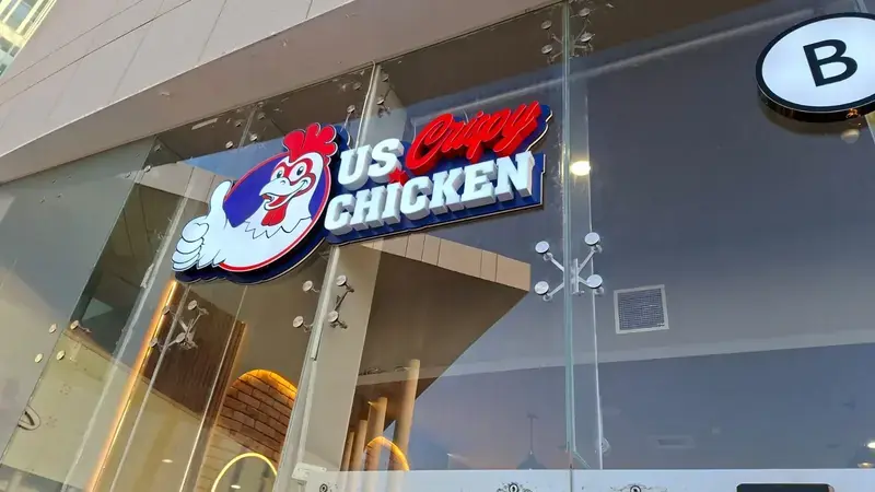 Contour-cut illuminated restaurant sign on a glazed shopfront, white and red 3D letters on navy