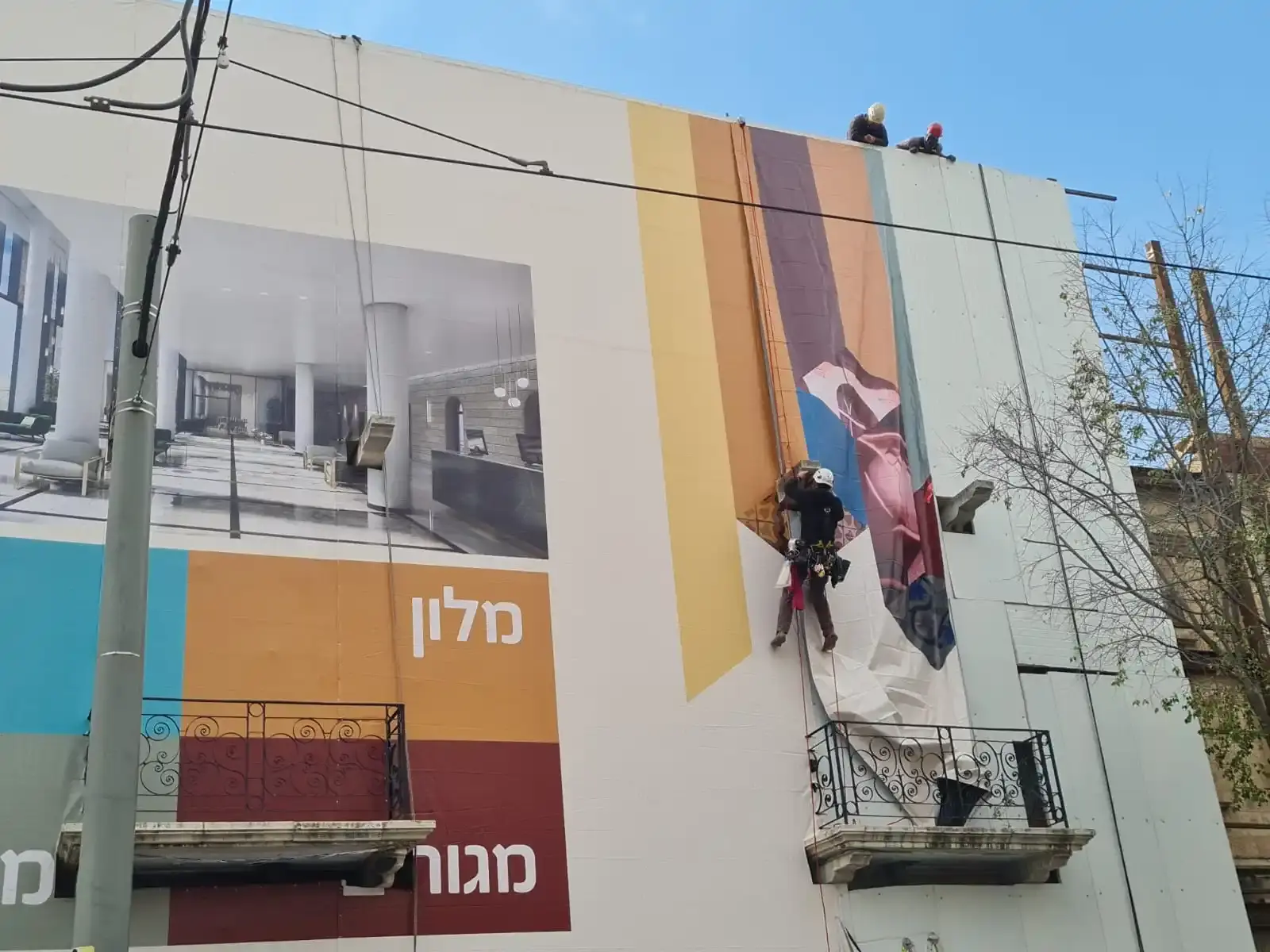Trabajadores instalando banner publicitario de gran tamaño en edificio de hotel — SignWorks